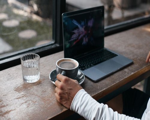 A glass of water and a laptop on a wooden desk, symbolizing work breaks